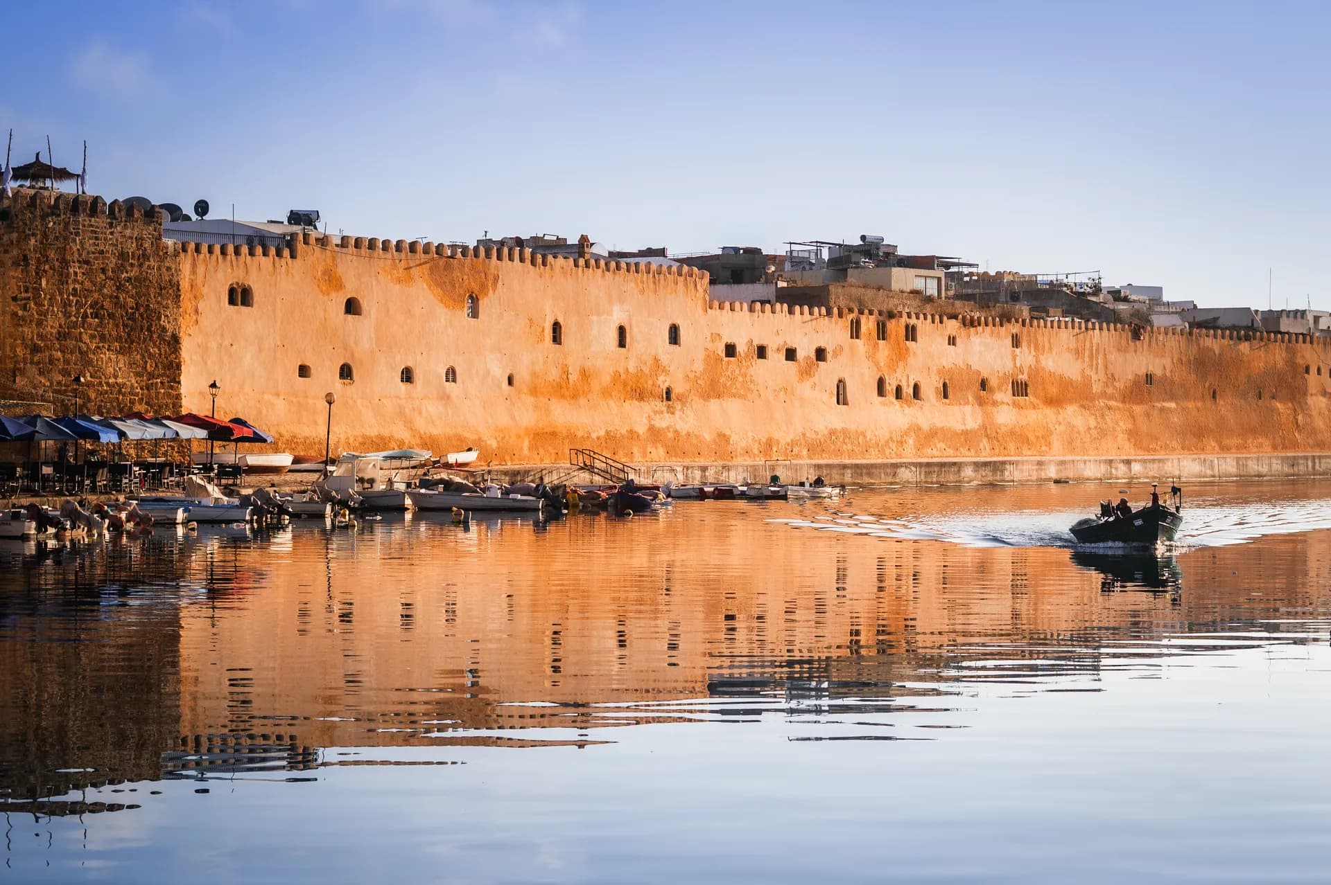 Les remparts de la kasbah de Bizerte baignés de lumière dorée, reflétés dans les eaux du vieux port