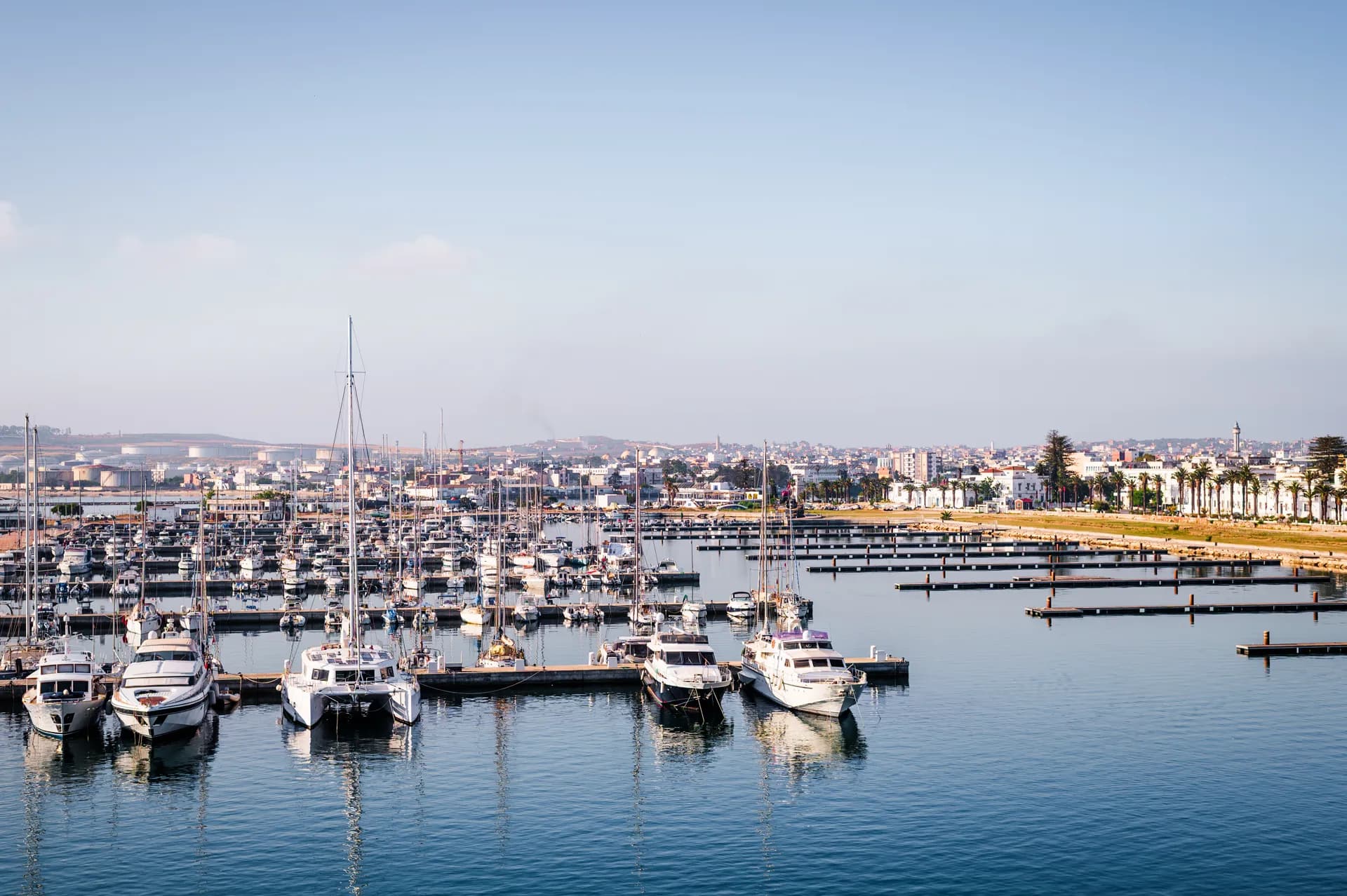 Voiliers et yachts amarrés le long des pontons de la Marina de Bizerte, la ville en arrière-plan