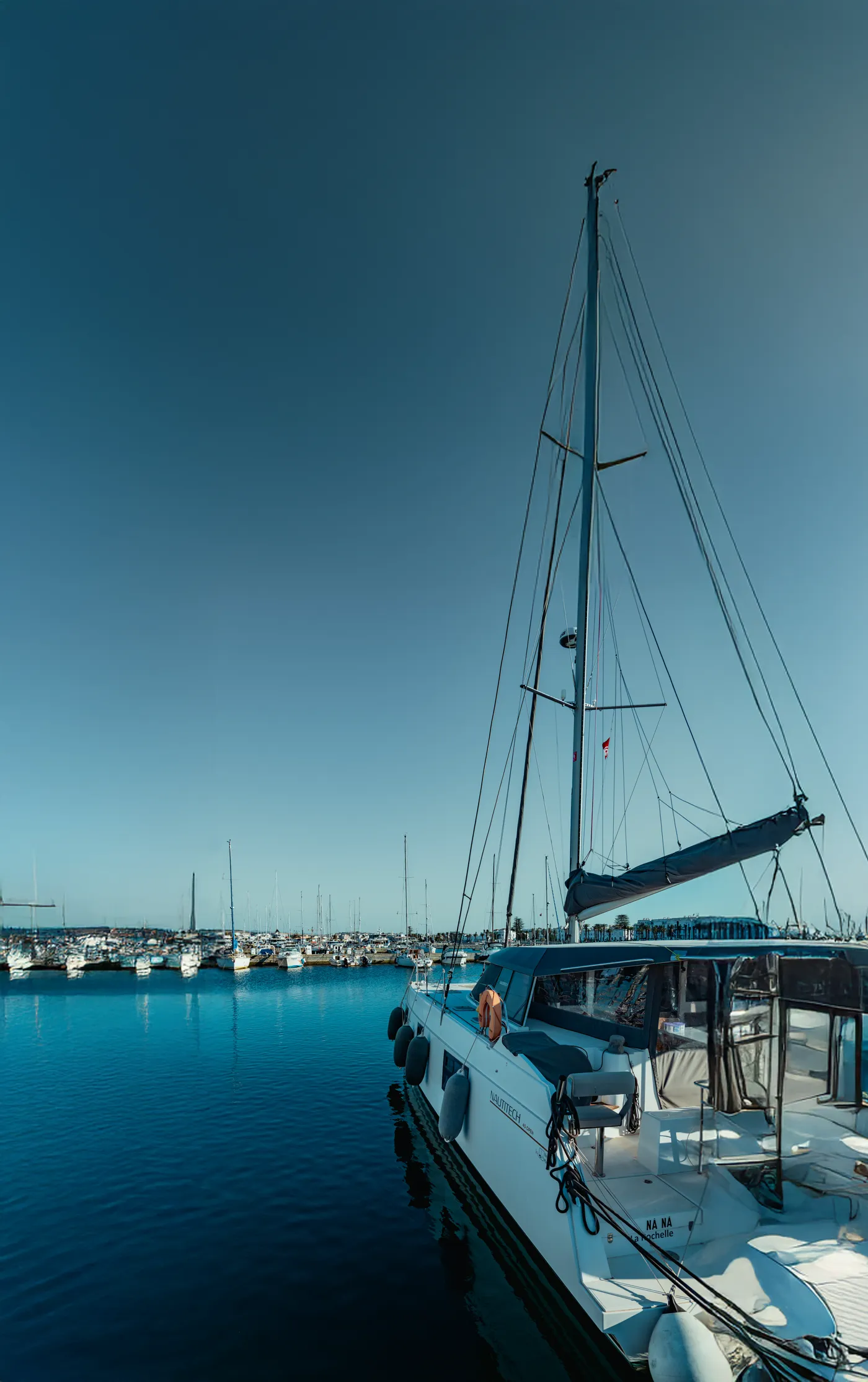 Voilier amarré le long d'un ponton de Marina Bizerte, le plan d'eau abrité et les quais de la ville en arrière-plan